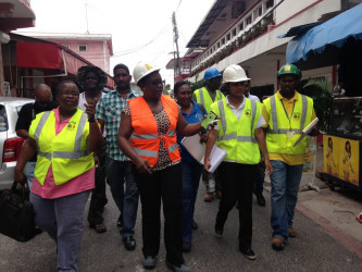 Junior Social Protection Minister Simona Broomes (in orange) walks through Pitt Street with her team of inspectors (David Papannah photo)