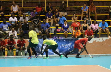 Aroydy Branford (right) of the National U-21 unit on the attack after skipping past two Hikers players during their matchup at the National Gymnasium in the Diamond Mineral Water Hockey Festival 
