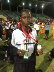 Track star in the making Kenisha Phillips proudly displays the two gold medals she won at the just concluded 2015 National School’s Cycling, Swimming and Track and Field Championships en route to breaking both records. 