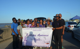 Christopher France (right) holding the banner after the walk ended at the seawall along with other supporters from UG and the Epilepsy Foundation.

