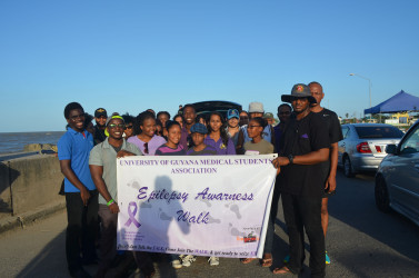 Christopher France (right) holding the banner after the walk ended at the seawall along with other supporters from UG and the Epilepsy Foundation.   
