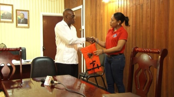 Public Relations Officer of MARAD, Akousa Mc Pherson (right) presents a life jacket to Region Ten Chairman, Renis Morian. (GINA photo)