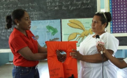 Sharmin Grey (right), a teacher of the Muritaro Primary School receives a life jacket from MARAD's Public Relations Officer, Akousa Mc Pherson (GINA photo)