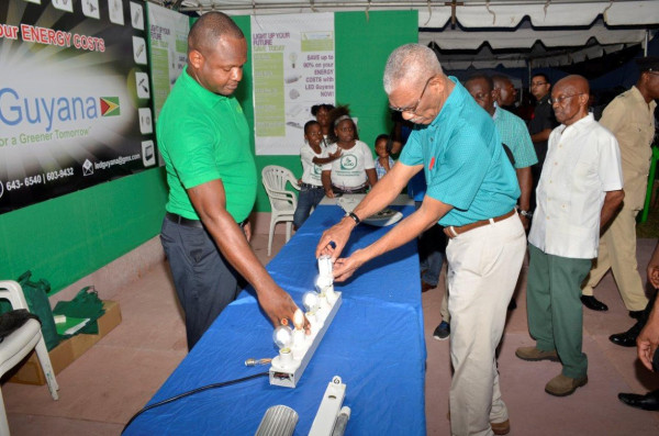 President David Granger installing an energy saving bulb at one of the booths on display at the "Green Expo" at the Parade Ground over the weekend. (Ministry of the Presidency photo). 