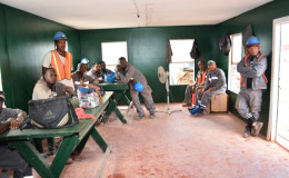 Workers listen to Minister Simona Broomes in their lunch room at the Kurubuka mining site