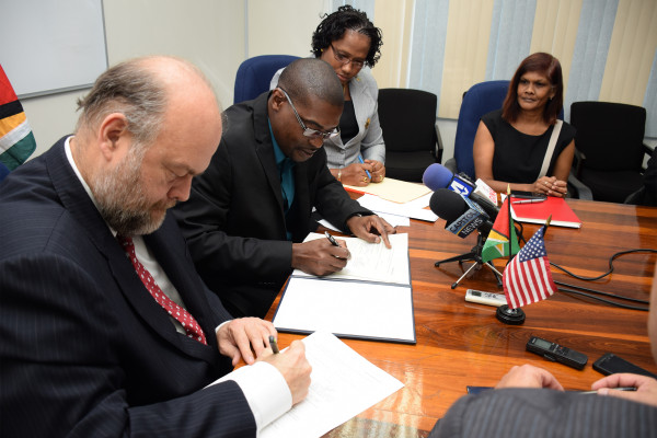 Minister of Public Infrastructure David Patterson (second from left) and US Ambassador to Guyana Perry Holloway (left) signing the memorandum of agreement between the GCAA and USA-TSA for support and cooperation in developing capacities and expertise in civil aviation. (GINA photo) 