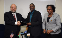 Minister of Public Infrastructure David Patterson (centre) and US Ambassador to Guyana Perry Holloway shake hands following the signing of the MOU between the GCAA and USA-TSA at the Ministry’s boardroom, Wight’s Lane.  Also in photo is Minister within the Ministry of Public Infrastructure Annette Ferguson (GINA photo) 