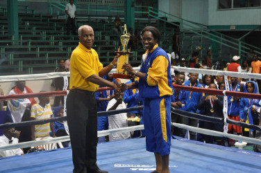 Barbados’ Kimberley Gittens receiving her female best boxer trophy of the Caribbean Development Goodwill Tournament which concluded Sunday night at the Cliff Anderson Sports Hall. 