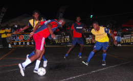Dennis Edwards (blue vest) of Channel-9 Warriors trying to control the ball while being challenged by Jamal Pedro of West Front Road as teammate Delon Williams (centre) and opposing player Hubert Pedro (right) look on.