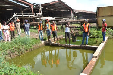 Workers stand at the rancid pond from which they are forced to dip water and which they reported has made them sick. (Social Protection Ministry photo)
