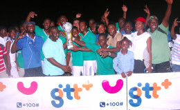 GTT Representative Eusi Francis (front row, second from left) handing over the championship trophy to Milerock captain Joel McKinnon while members and supporters of the team celebrate their hard-fought win over Victoria Kings in the GTT/Limacol Football Championship at the Mackenzie Sports Club ground
