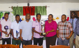 Captain of the victorious Milerock FC Joel McKinnon (centre) receiving the championship trophy from GTT PRO Allison Parker during the official Limacol/GTT Football Championship presentation ceremony while other members of his team, respective prize winners, sponsors and Petra Organization staff look on.
