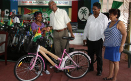 President David Granger presenting a bicycle to one of the children enrolled in the Sophia Literacy Programme at Congress Place yesterday, while Minister of Social Cohesion Amna Ally (right) and GAICO boss Komal Singh, who donated the bicycles to the Boats, Bicycles and Buses school transportation programme, look on. (Photo by Keno George)
