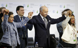 French Foreign Affairs Minister Laurent Fabius (C), President-designate of COP21 and Christiana Figueres (L), Executive Secretary of the UN Framework Convention on Climate Change, hold hands as they react during the final plenary session at the World Climate Change. (Reuters/Stephane Mahe)