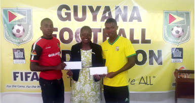 Alpha United’s Delon Lanferman (left) and Pele’s Jumane Somerset collecting their plane ticket from GFF Vice President Attorney-at-Law Thandi McAllister at the federation’s office prior to their departure for the MLS Combine in Curacao