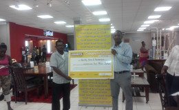 Mr Deonandan (left), one of the $2 million prize winners and Marketing Manager Pernell Cummings pose with the award cheque.
