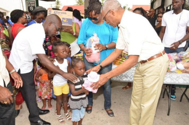 President David Granger (right) presenting toys to the children who assembled at Wilson Gas Station in Buxton Village. (Ministry of the Presidency photo) 