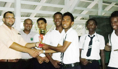 At the sixth Berbice Inter-School Chess Championship held in November, Skeldon High School emerged victorious. Veral Felix of Orealla Primary created history for his school by placing second in the individual category of the competition. Darwin London of the Berbice Educational Institute was first. In photo, one of the winners receives a trophy after the competition.