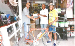 In picture Neal Lewis of the Lewisons’ store at Rose Hall Town presents a cheque of an undisclosed sum to organizer Randolph Roberts at  Rose Hall Town, Corentyne, Berbice  while young cyclist Zamar Khan displays his new bike.
 

