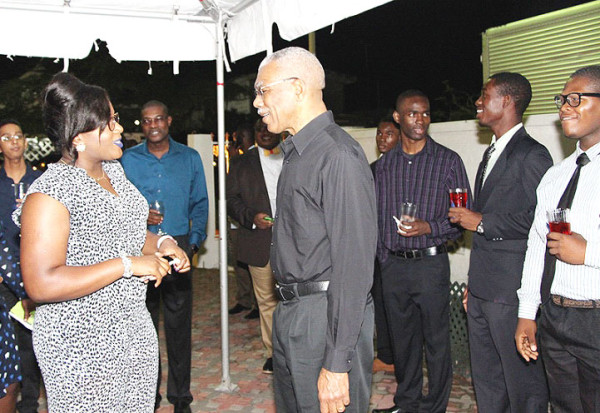 President David Granger shares a light moment with Simona Broomes (left), one of the overseas-based Guyanese students at the event Monday evening and the daughter of the Minister within the Ministry of Social Protection. (Ministry of the Presidency photo)