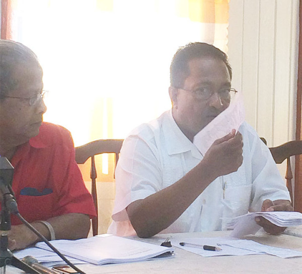 GAWU General Secretary Seepaul Narine holds up a payslip for a sugar worker while President of the union, Komal Chand looks on. 