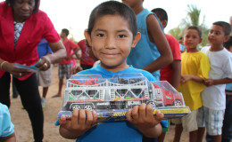 A St Ignatius boy beams as he displays his new toy truck. Minister of Social Cohesion, Amna Ally and  First Lady Sandra Granger yesterday distributed a large quantity of toys to children of St Ignatius, Rupununi. The visit was part of a distribution of bicycles to help ensure children get to school. (Ministry of the Presidency photo)