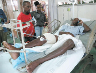 National senior footballer Keron Cummings speaks on his cell phone while warded at the Port-of-Spain General Hospital after being shot in the leg after returning home from a party on Saturday. Cummings was expected to join the national team in camp ahead of the Copa America Centenario match against Haiti on January 8