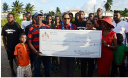 Prime Minister Moses Nagamootoo (centre) and wife Sita Nagamootoo (next to him) hands over the cheque to Founder of the Group Beryl Haynes in the presence of community members. (GINA photo)