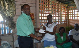 
Minister of State, Joseph Harmon handing over the $215,000 to Patricia Lynch of Angoy's Avenue, New Amsterdam. (Ministry of the Presidency photo)