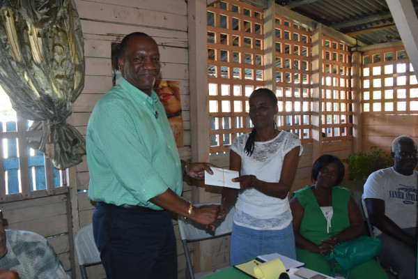  Minister of State, Joseph Harmon handing over the $215,000 to Patricia Lynch of Angoy's Avenue, New Amsterdam. (Ministry of the Presidency photo)