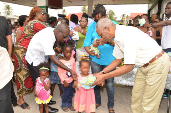 President David Granger (right) presenting toys to the children who assembled at Wilson Gas Station in Buxton Village. (Ministry of the Presidency photo)