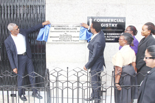 President David Granger (at left) and Attorney-General Basil Williams unveiling the plaque yesterday to commission the Commercial and Land registries, now located at the former New Building Society headquarters at Avenue of the Republic. (Keno George photo)