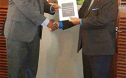 Prime Minister Moses Nagamootoo (right) receiving the report from Nigel Hughes yesterday.