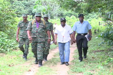Ministers of Foreign Affairs, Carl Greenidge (second from right) and Guyana Defence Force Chief of Staff, Brigadier Mark Phillips (left in front row)  and other ranks of the force entering the village of Kaikan, Region Seven. (GINA photo)