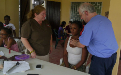  Linda (left) looking on as Dr. Russel Horn examines a patient