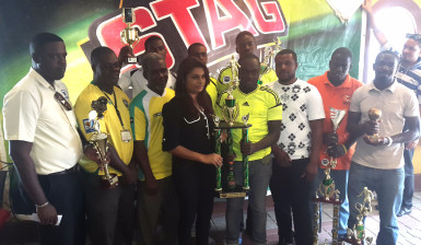 PRO of Ansa McAL Darshanie Yussuf presents the large championship trophy and cash prize to some club members of the Grove Hi Tech unit.