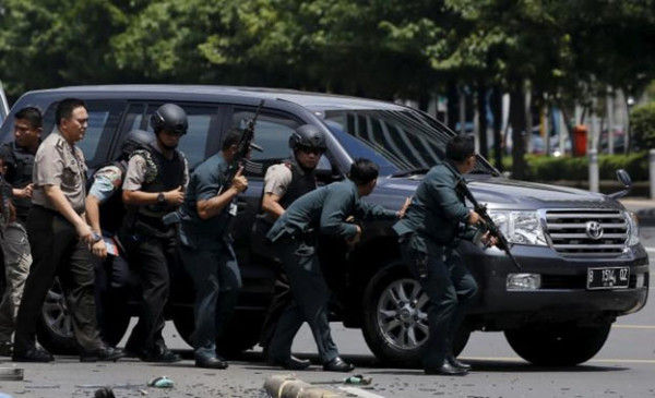 Indonesian police hold rifles while walking behind a car for protection in Jakarta January 14, 2016.  Reuters/Beawiharta 