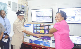 Junior Public Infrastructure Minister Annette Ferguson (right) handing over a 48-inch monitor from the Demerara Harbour Bridge to Commissioner of Police Seelall Persaud
