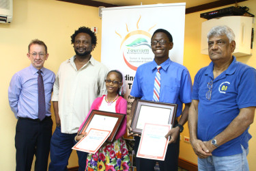  Winners of the THAG essay competition Victoryne Mohabir and Omari Obaseki Joseph (at centre) flanked by competition judges Dr. Steve Surujbally (at right) and Ruel Johnson (second left) along with President of THAG Shaun McGrath (extreme left)