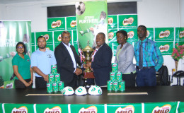 Troy Mendonca, third from right, receives the championship trophy from Nestle Caribbean’s Business Development Manager Sudesh Mahase in the presence of members of the Ministry of Education and the GFF.
