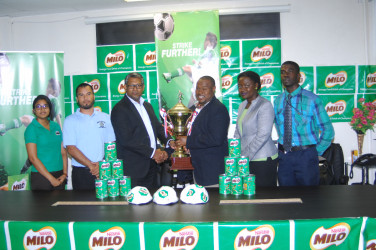 Troy Mendonca, third from right, receives the championship trophy from Nestle Caribbean’s Business Development Manager Sudesh Mahase in the presence of members of the Ministry of Education and the GFF. 