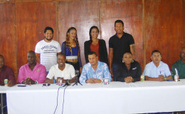 Cricketers Ramnaresh Sarwan (standing back left) and Johnathan Foo (standing back right) pose with the Unity T20 cheerleaders while sitting at the head table are the organizers and sponsors. PRO Sean Devers is centre and Digicel’s Louanna Abrams third from right. (Orlando Charles photo)