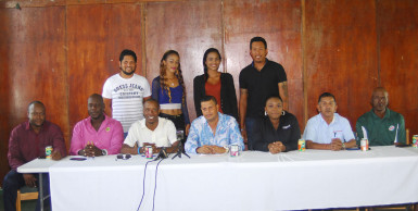Cricketers Ramnaresh Sarwan (standing back left) and Johnathan Foo (standing back right) pose with the Unity T20 cheerleaders while sitting at the head table are the organizers and sponsors. PRO Sean Devers is centre and Digicel’s Louanna Abrams third from right. (Orlando Charles photo)