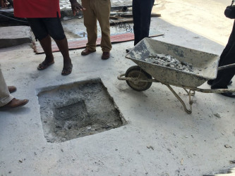 A sealed manhole being broken to facilitate cleaning of the drains at Fifth Street, Alberttown (David Papannah Photo) 
