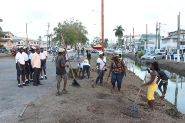 Town Clerk Royston King (standing at left with hands behind back) looks on as city workers clean the vacated Merriman Mall strip, between Orange Walk and Cummings Street. (Photo by Keno George)