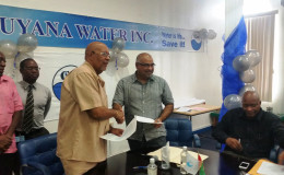 The agreement being exchanged between GWI Chief Executive Richard Van West-Charles (left) and IAST Director Dr Suresh Narine. (GWI photo)