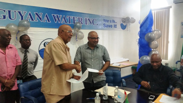 The agreement being exchanged between GWI Chief Executive Richard Van West-Charles (left) and IAST Director Dr Suresh Narine. (GWI photo)