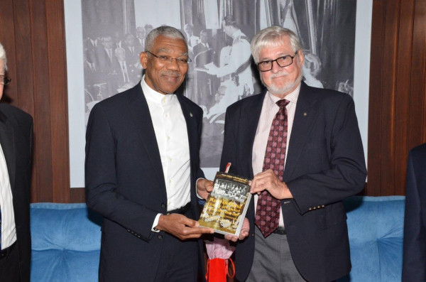 President David Granger (left) receives a copy of the book “Hand-in-Hand History of Cricket in Guyana 1865-1897” from the insurance company’s board member  John Carpenter. (Ministry of the Presidency photo)