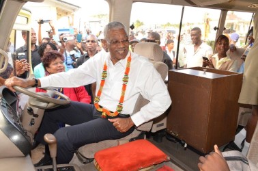 President David Granger at the wheels of one of the buses. (Ministry of the Presidency photo)