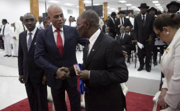 Haiti’s outgoing President Michel Martelly (2L) shakes hands with the Senate President Jocelerme Privert (C) in presence of the Prime Minister Evans Paul during a ceremony marking the end of Martelly’s presidential term, in the Haitian Parliament in Port-au-Prince, Haiti yesterday. REUTERS/Andres Martinez Casares